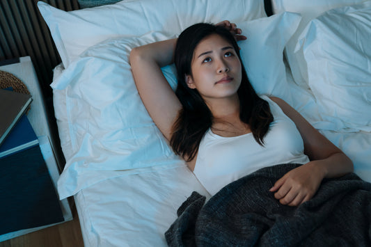 Woman laying in bed awake and frustrated