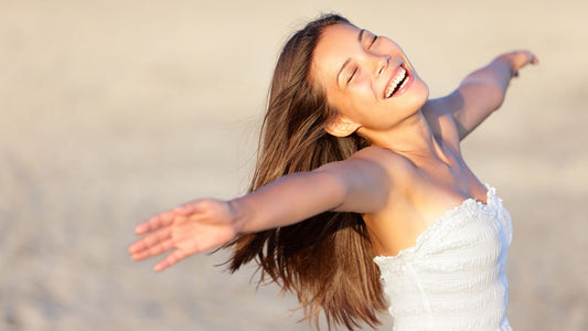 Woman with arms wide open tilting her head back and smiling on a sunny day