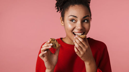 Young woman in a red sweater eating a chocolate chip cookie